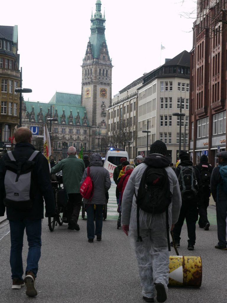 Demozug läuft in Richtung Rathausmark. das Rathaus ist im Hintergrund zu sehen, Demonstrierende von hinten fotografiert